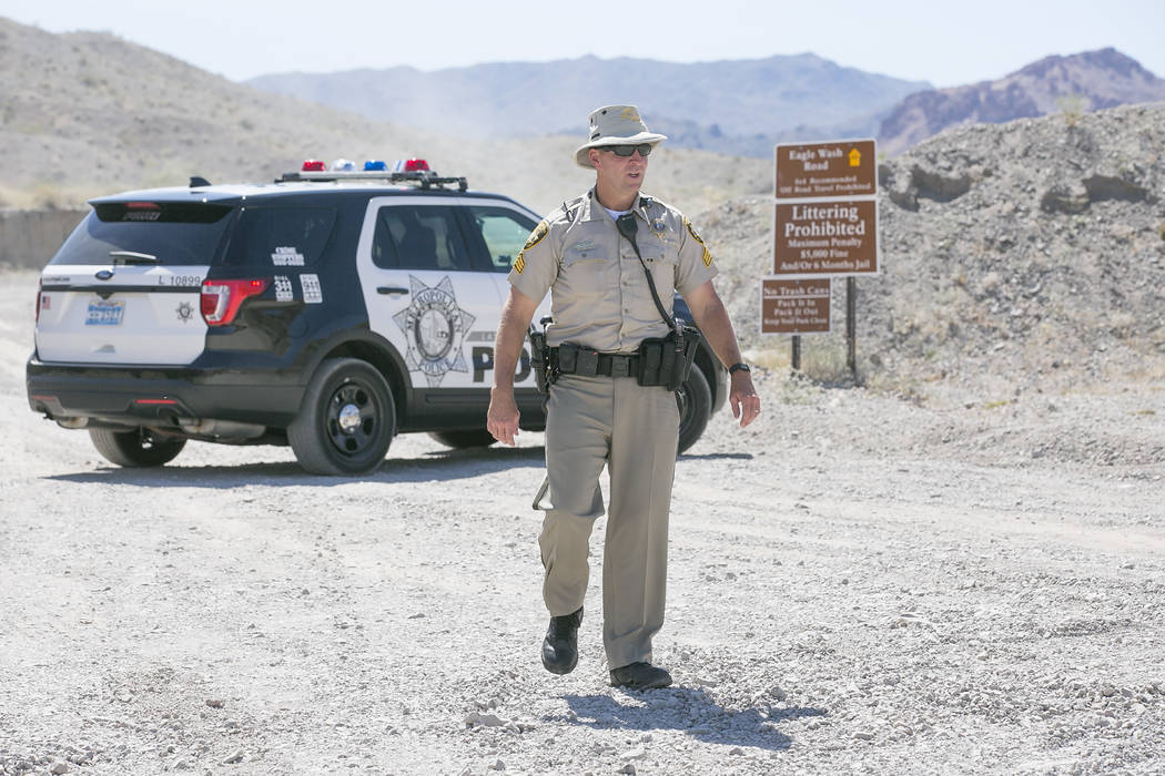 Bridget Bennett Las Vegas Review-Journal @bridgetkbennett
Metropolitan Police Department Sgt. Eugene Gallagher stand guard at an entrance to Eagle Wash Road, which leads to the crime scene, at Lak ...