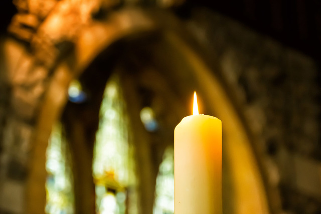 Church candle with stained glass window in the background