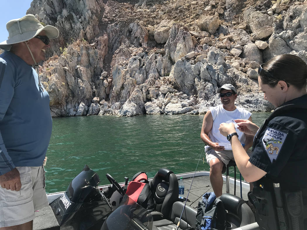 Hali Bernstein Saylor/Boulder City Review Brittany Frolick, a game warden with the Nevada Department of Wildlife, checks the fishing licenses of Keith Hoffman of Boulder City, left, and Matt Hoffm ...