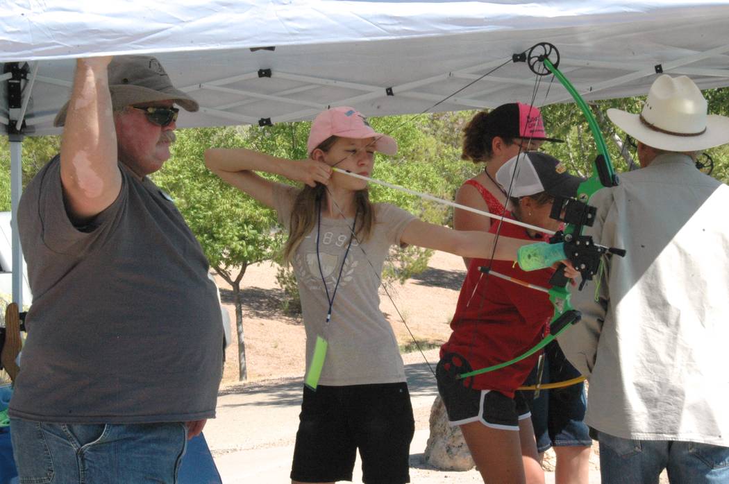 Jayme Sileo/Boulder City Review Nevada Department of Wildlife volunteer William Bly helped staff the bowfishing activity tent where Annalise Johnson and others practiced shooting fake fish with a ...