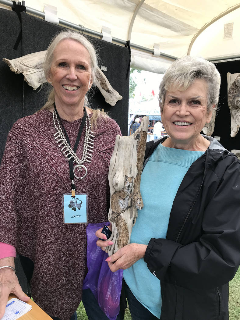 Hali Bernstein Saylor/Boulder City Review Boulder City artist Lynne Jordan, left, sells a pyrographic sculpture of squirrels on a piece of driftwood to Doni Stewart of Las Vegas on Sunday, Oct. 7, ...