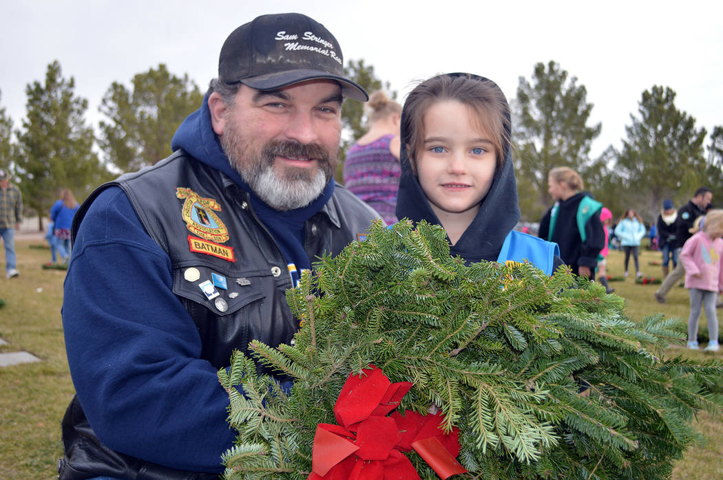 Mike Keeton and his daughter, Kenzie, lay a wreath on a veteran's grave at the Southern Nevada Veterans Memorial Cemetery during the 2017 observance of Wreaths Across America. This year's event wi ...