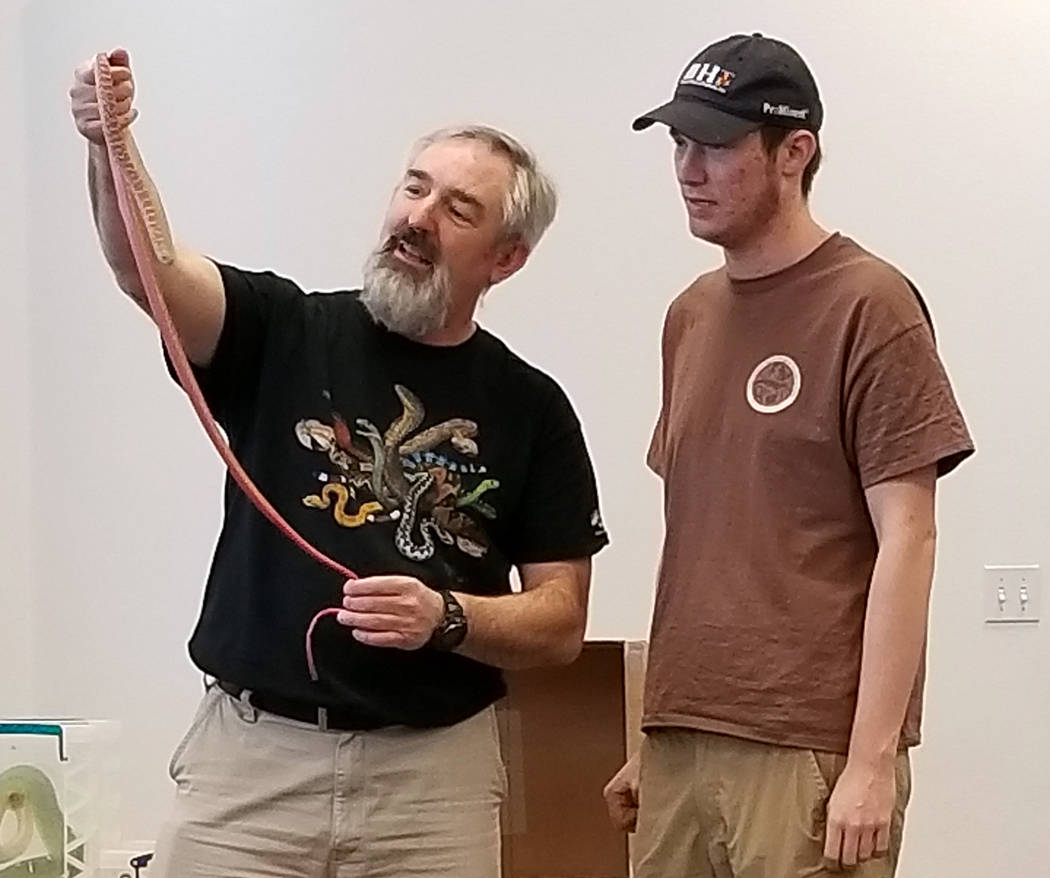 (Celia Shortt Goodyear/Boulder City Review) Chuck Meyer, left, shows his red racer snake with his son, Charlie, at the Boulder City Library on Jan. 3. The animal event was part of the winter readi ...