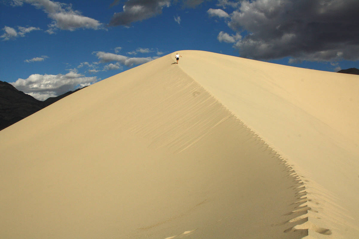 (Deborah Wall) A hiker makes his way up the soft sand at Eureka Dunes at Death Valley National ...