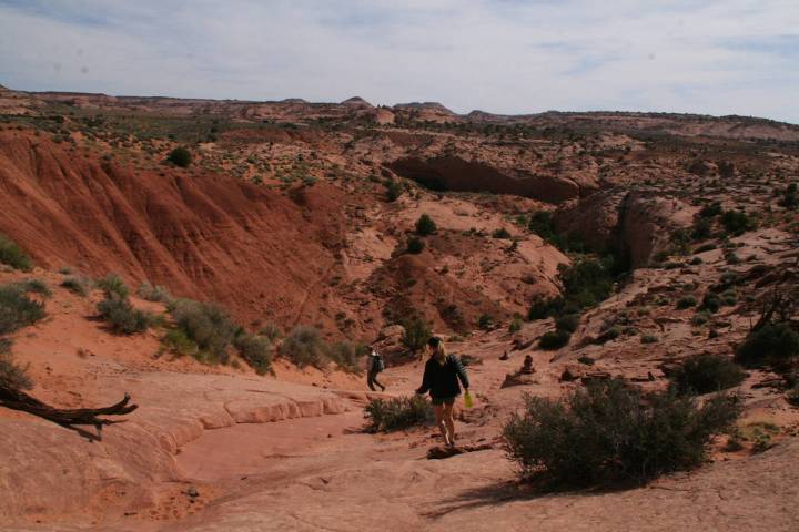 (Deborah Wall) From the trailhead hikers head down the slickrock using cairns to guide the way ...