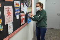 Boulder City Library Cataloging Department Manager Jill Donahue takes down a sign about masks b ...