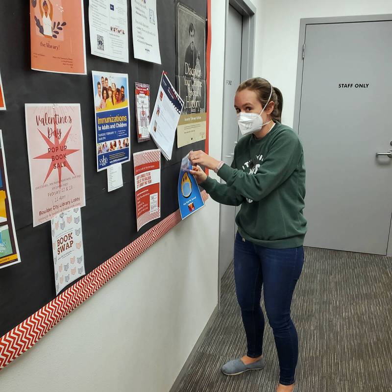 Boulder City Library Cataloging Department Manager Jill Donahue takes down a sign about masks b ...