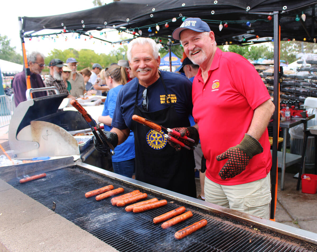 Rotarians Dale Ryan and Doug Scheppmann were all smiles as they served up bratwursts and hotdog ...