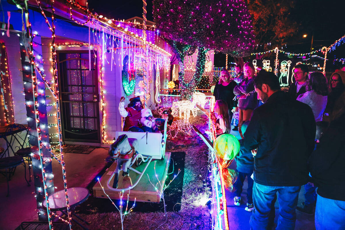 People admire Christmas decorations in the yard of Dale Ryan and Dyanah Musgrave on Sunday, Dec ...