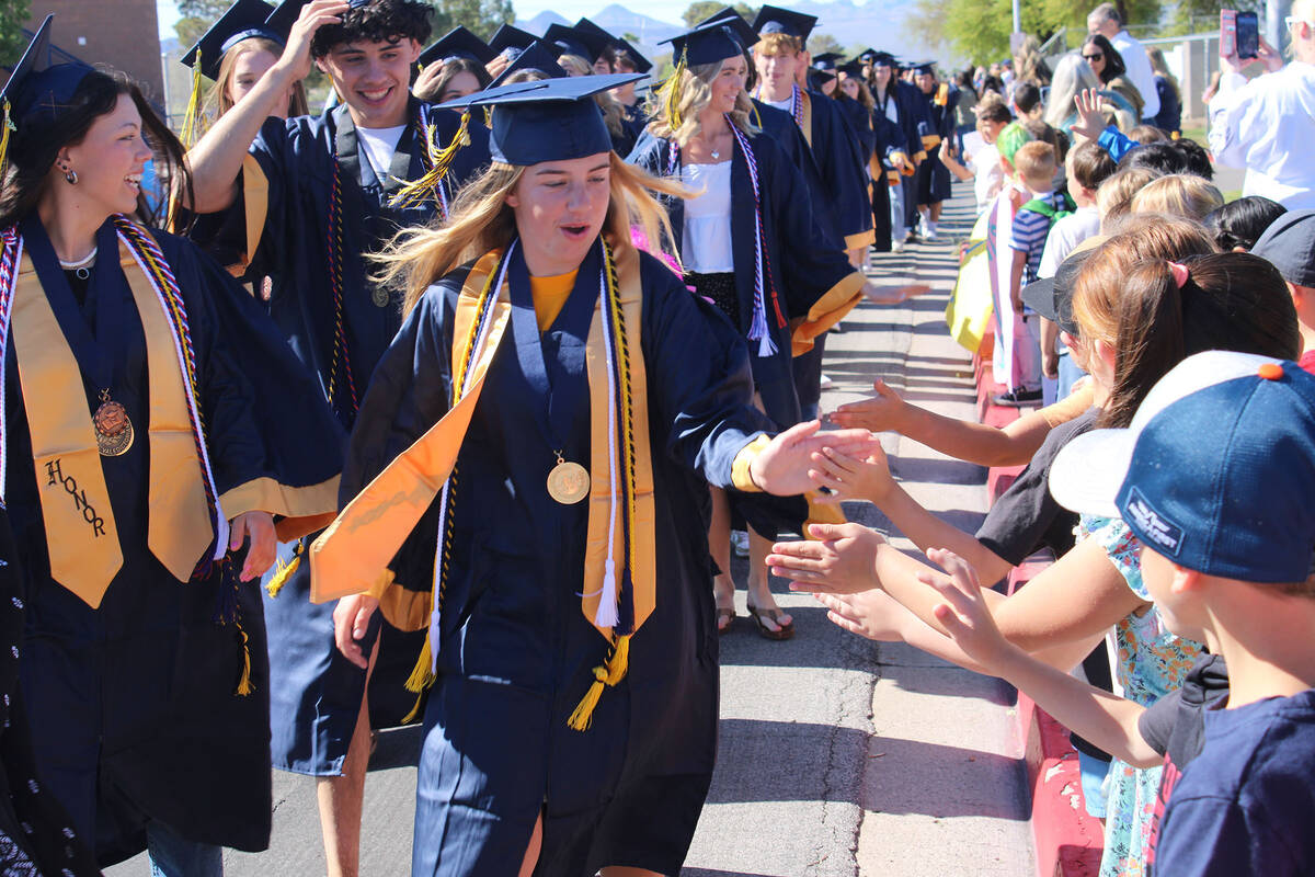 Indy Ruth, student body president, slaps the hand of an elementary student, while right behind ...