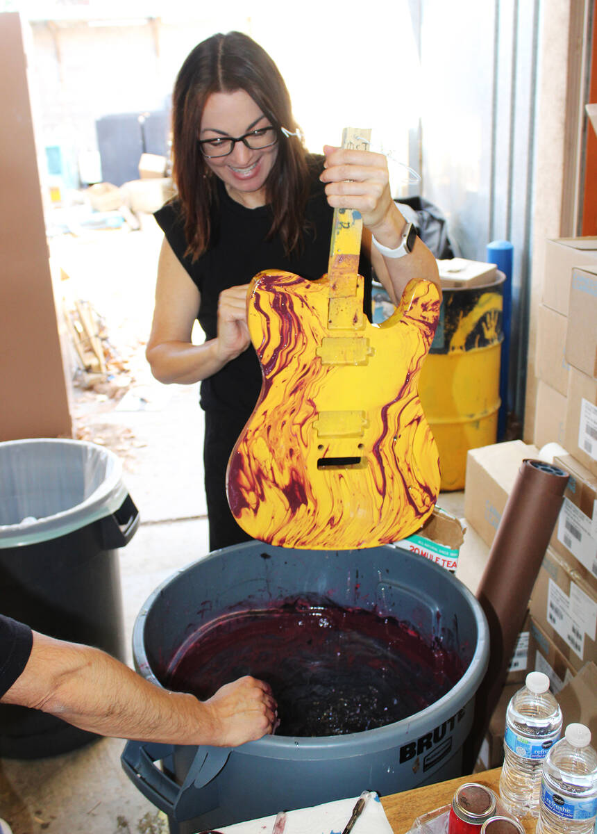 Band teacher Stacy Toal looks over her guitar after dipping it in paint to reflect the colors o ...