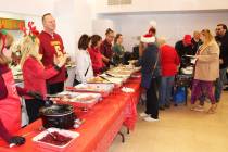 Volunteers on the left, prepare as another wave of people entered the free Christmas dinner, ho ...