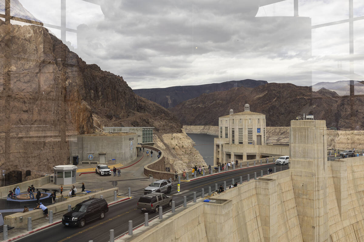 The Colorado River flows into the Hoover Dam as seen through the windows of an observation deck ...