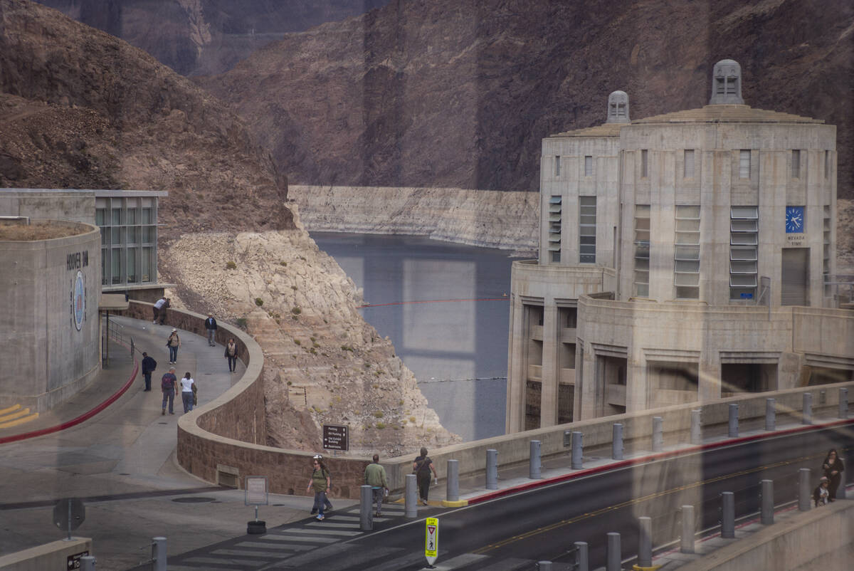 The Colorado River flows into the Hoover Dam as seen through the windows of an observation deck ...